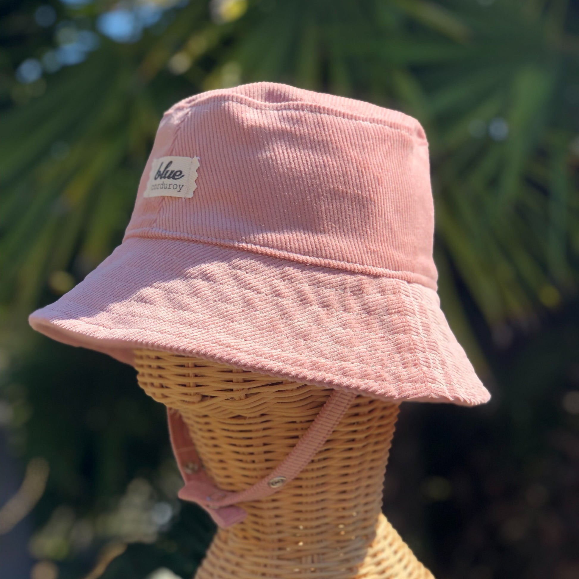 Side view of pink corduroy bucket hat for babies with chin straps