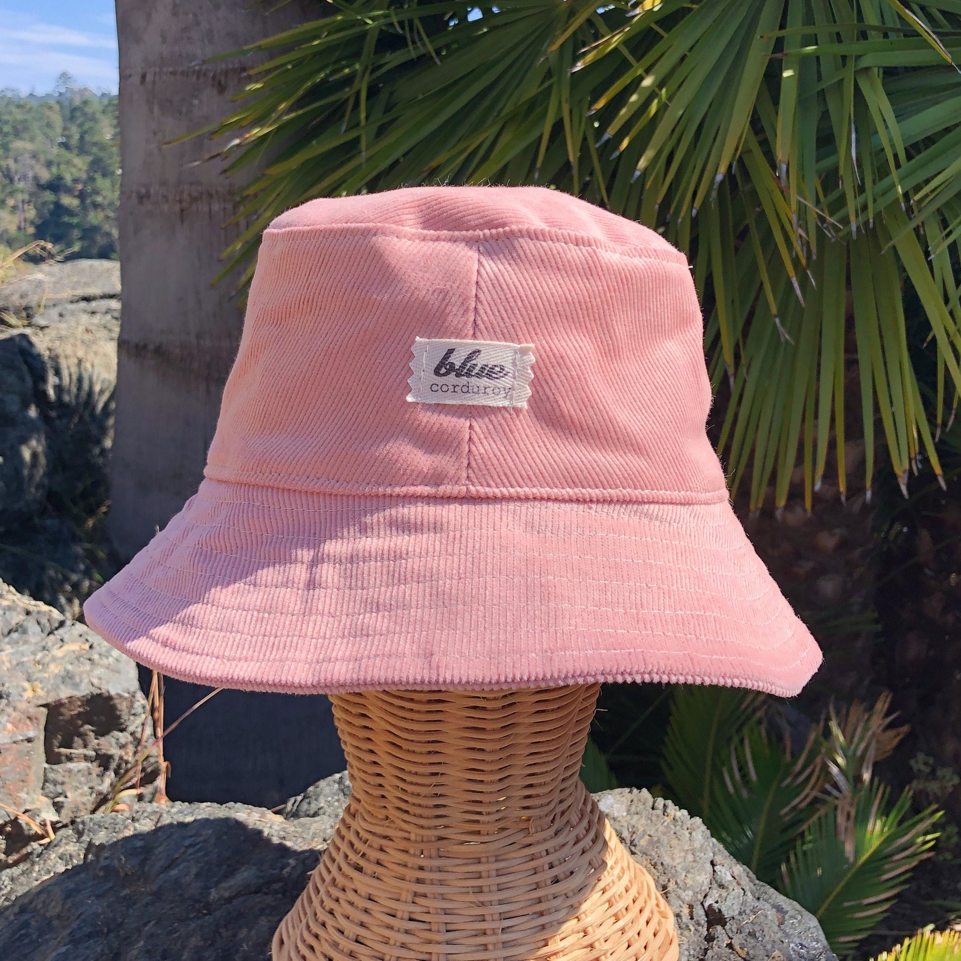 Pink corduroy bucket hat on blonde girl at beach.