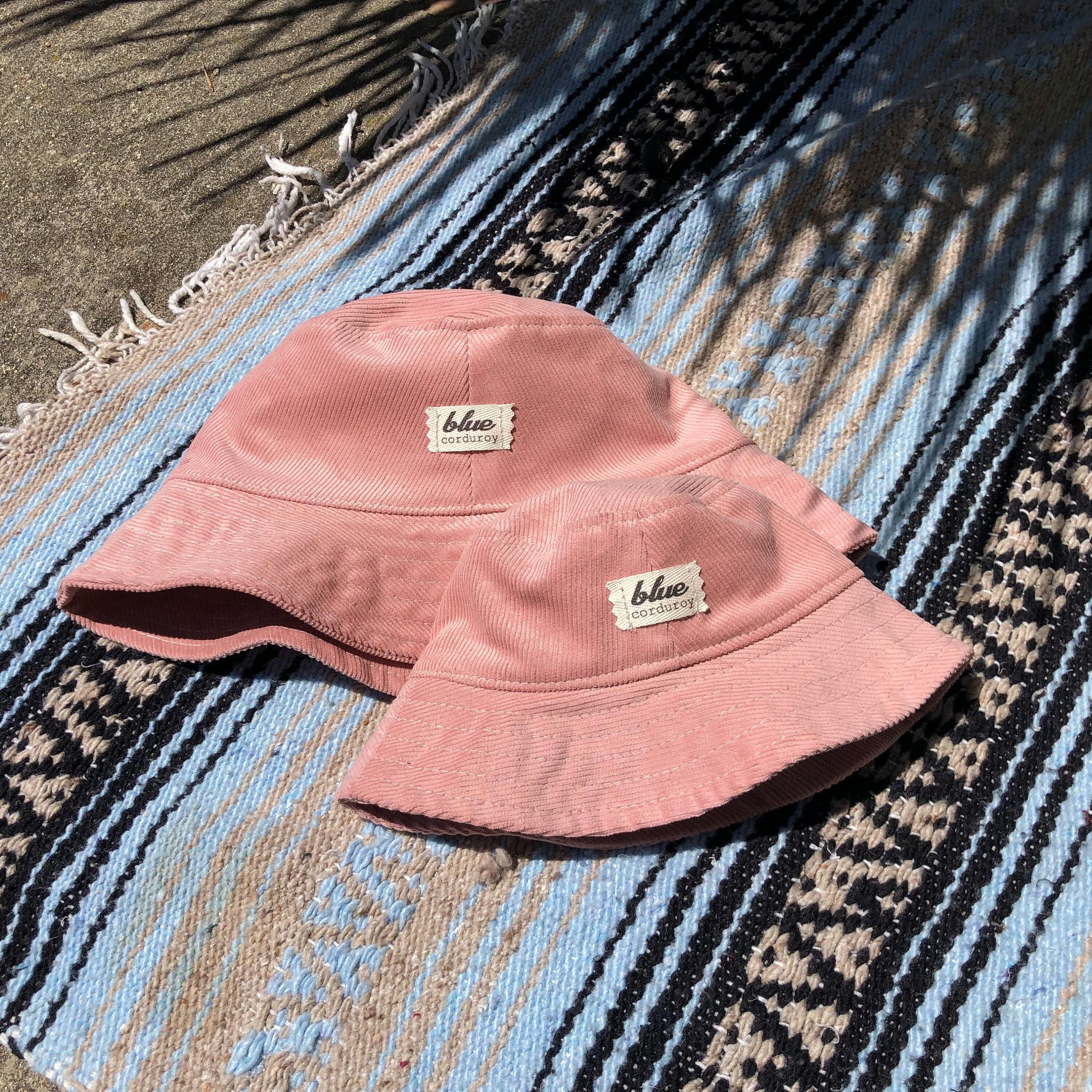 Pink Corduroy Bucket Hat Set for Mommy and Baby laying on beach towel.