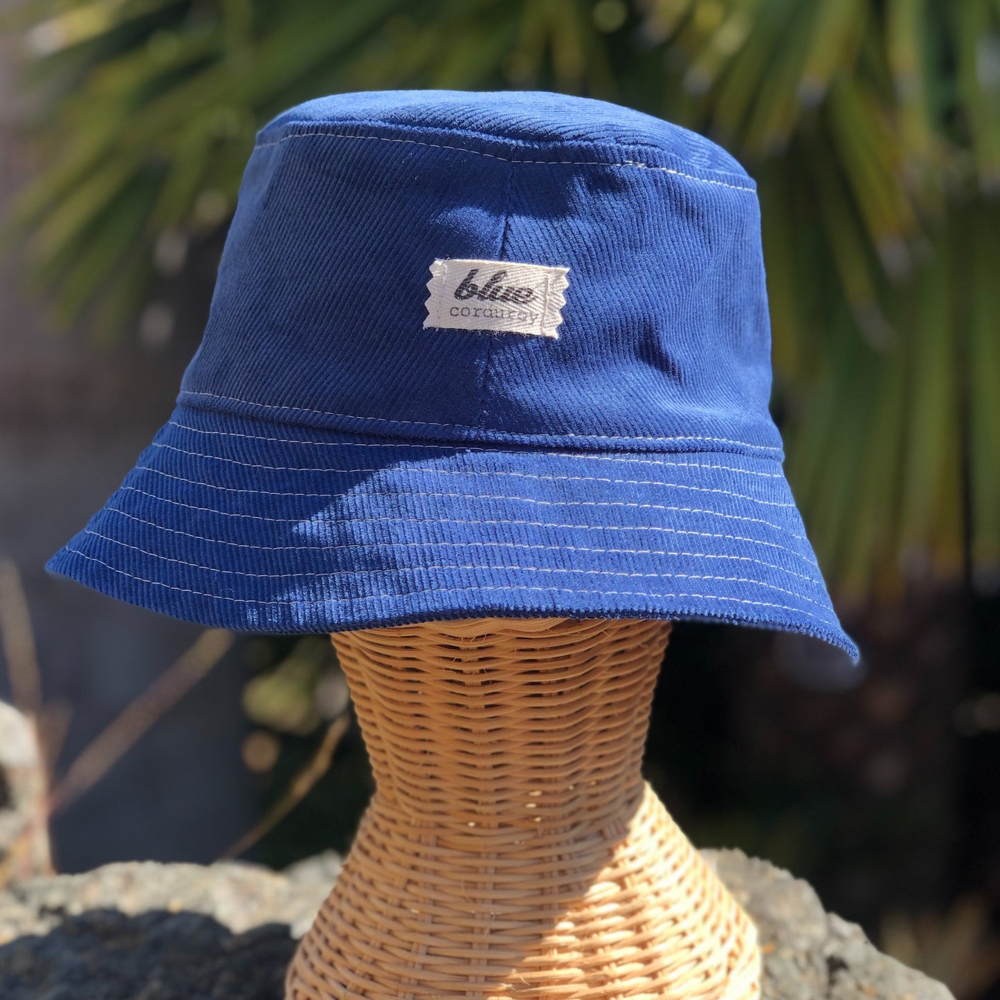 Bright blue corduroy bucket hat outside on rattan mannequin head