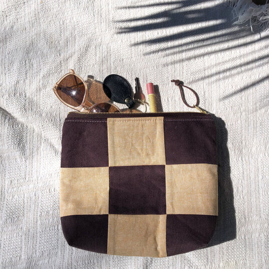 Brown and tan checkered zipper pouch holding sunglasses, keys and lipstick.