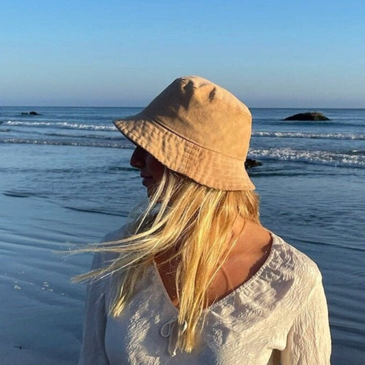 Woman on beach wearing tan corduroy bucket hat.