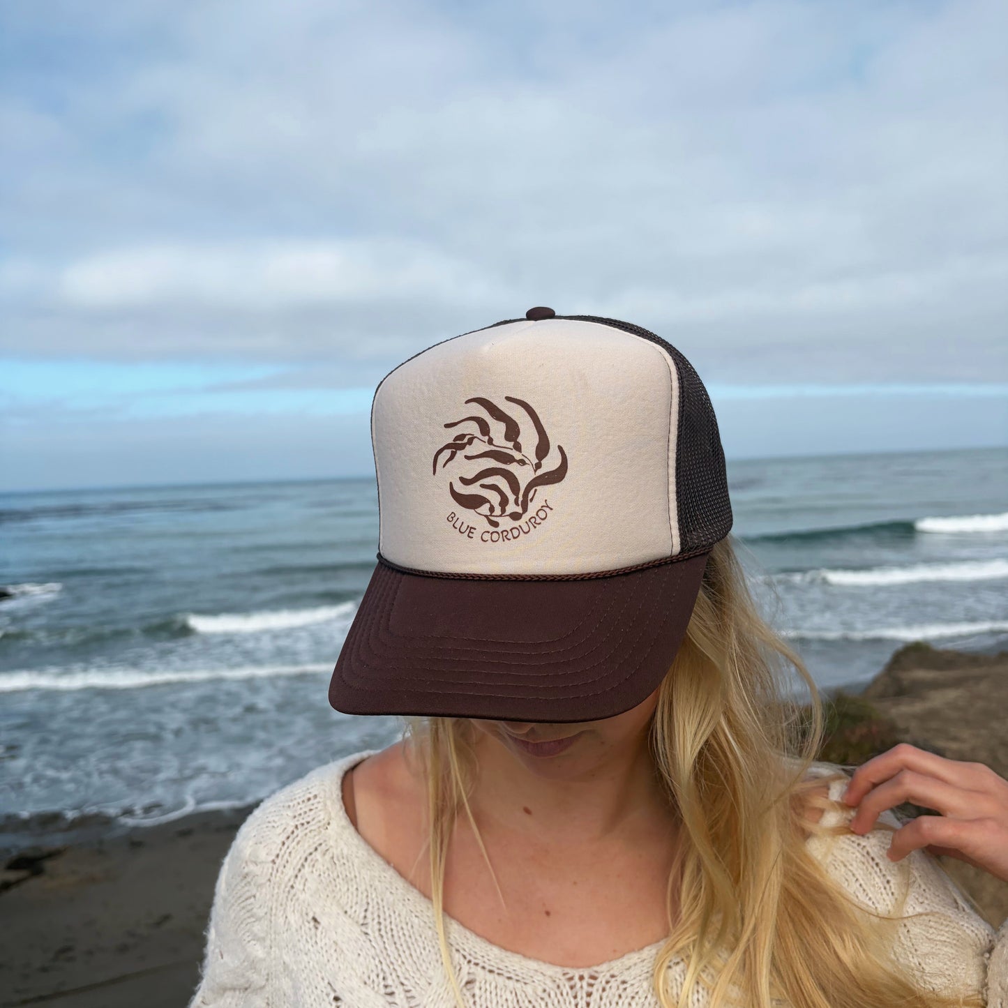 Person wearing a cap with a kelp logo on a beach